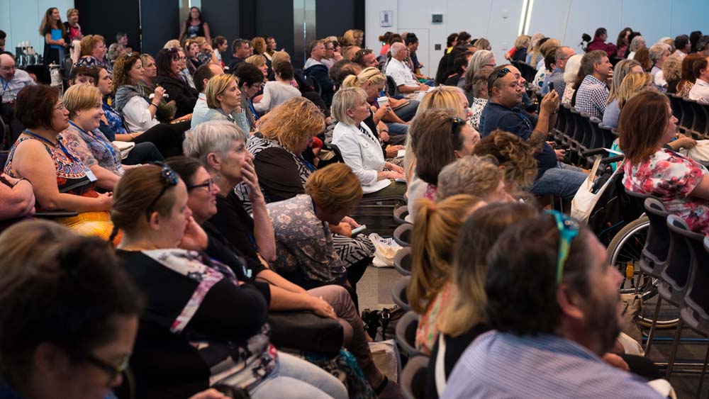 A conference room full of people listening to a speaker