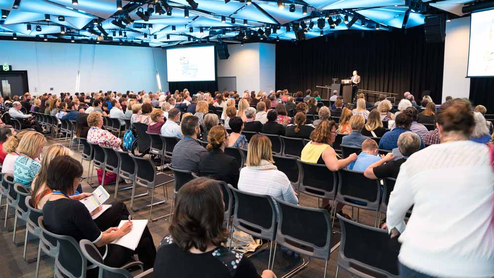 A conference room full of people listening to a speaker