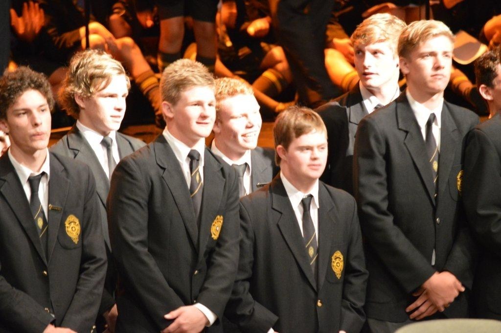 a group of well dressed young men at a high school graduation. One of them in the middle has down syndrome